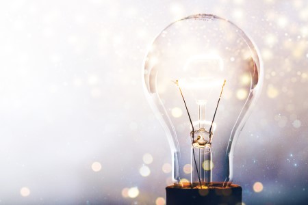 An element lightbulb is begining to glow, The focus is catching particles shimmering like pixie dust around the outside..