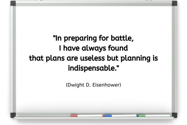 A framed white board with a red, blue and green pen sat on the ledge underneath. The text on the board reads: "In preparing for battle, I have always found that plans are useless but planning is indispensable." (Dwight D. Eisenhower)