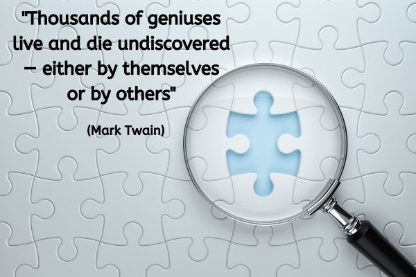 Looking down from above, a jigsaw that is made up of blank white pieces is almost complete. Slightly to the right of centre there is one piece missing showing whatever this is resting upon is pale blue. A round hand held magnifying glass is sat ontop of that gap with the missing space positioned centrally of the magnifying circle.
The text reads: "Thousands of geniuses live and die undiscovered — either by themselves or by others" (Mark Twain)
