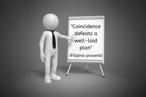 A 3D faceless human figure is stood to the right of a flip chart and stand. The figure is wearing a black tie and is pointing to the flip chart. The words on the flip chart reads: "Coincidence defeats a well-laid plan" (Filipino proverb)