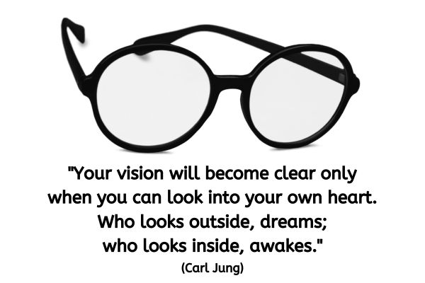 The image features a simple yet powerful depiction of a pair of round, black-rimmed glasses, centered against a plain white background. The glasses, iconic and timeless in style, are sharp and prominent, with clear lenses that allow for a straightforward view through them. This minimalist presentation emphasizes the glasses themselves without any distractions, focusing on the clarity and potential they symbolize for vision and perception. Above the glasses, there is a profound quote by Carl Jung: "Your vision will become clear only when you can look into your own heart. Who looks outside, dreams; who looks inside, awakes."