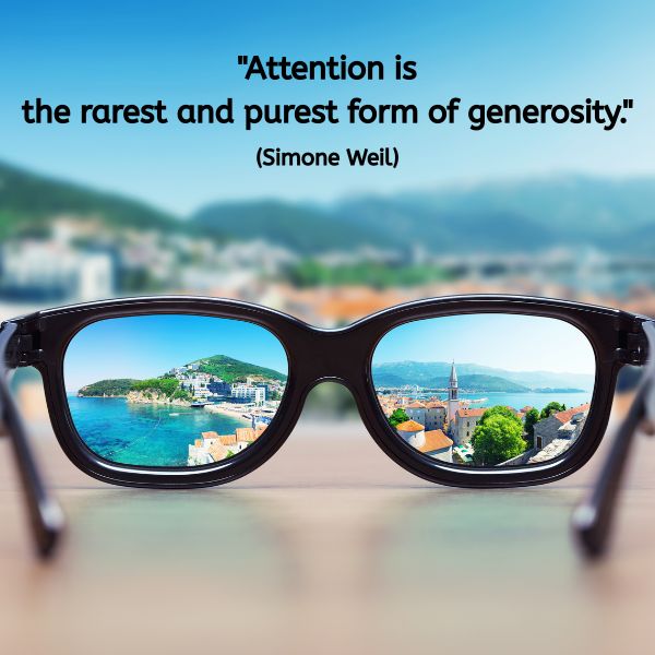 Quote reads: “Attention is the rarest and purest form of generosity.” (Simone Weil). Behind the quote, a pair of glasses sits on a table. The background outside the glasses is blurred, but through the lenses, a vivid and colourful coastal town comes into sharp focus. The image highlights clarity through focused attention.