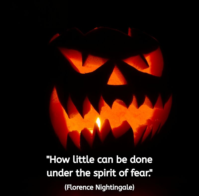 A glowing carved pumpkin with a fierce expression sits in darkness, its candlelight casting an orange glow. Below it, in white text, is the quote: “How little can be done under the spirit of fear.” (Florence Nightingale) The image evokes both playful Halloween spookiness and a reflection on the nature of fear.