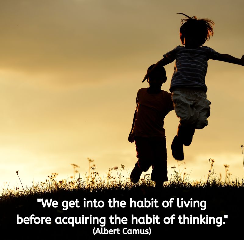 Image of two children playing outdoors at sunset. One child is mid-jump, arms outstretched, while the other stands nearby in silhouette against a golden sky. The mood feels joyful and free. Centered white text reads: "We get into the habit of living before acquiring the habit of thinking." (Albert Camus)